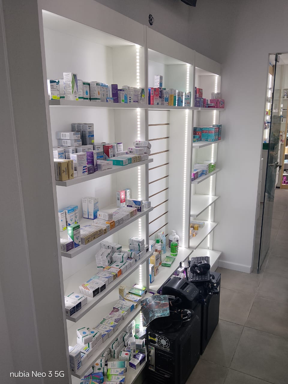 Equipos informáticos junto a estanterías en una farmacia